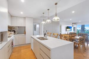 a kitchen with white cabinets and a dining room at Bliss the Beach Jervis Bay in Huskisson