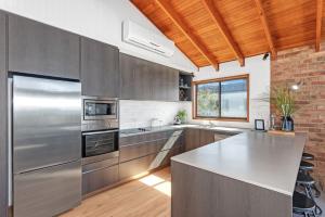 a kitchen with stainless steel appliances and a brick wall at Beachcombers on Collingwood Beach in Vincentia