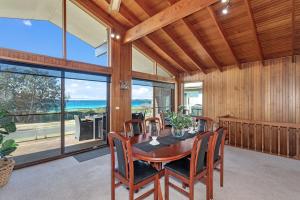a dining room with a table and chairs and a large window at Beachcombers on Collingwood Beach in Vincentia +8 photos