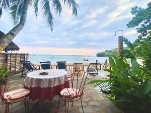 een tafel en stoelen met de oceaan op de achtergrond bij villa Mena in Nosy Be
