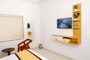 - une chambre avec un lit et une télévision murale dans l'établissement Serene Stay, à Alappuzha