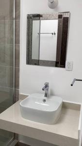a white bathroom with a sink and a mirror at Hermosa casa en Acapulco con club de Playa. in Acapulco