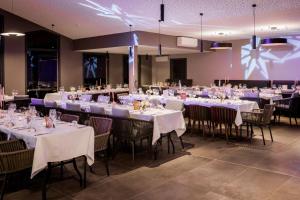 サラジーにあるSarana Hôtel & Spaの白いテーブルクロスの椅子とテーブルが備わる宴会場