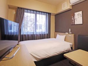 um quarto de hotel com uma cama e uma janela em Hotel Route Inn Tagajo-Eki Higashi em Tagajo