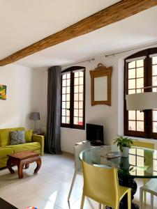 a living room with a glass table and yellow chairs at La Maison du Courtil, Citron-Caramel in Moustiers-Sainte-Marie