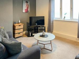 a living room with a couch and a tv and a table at Ivy Court Apartment in Rothesay