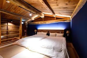 1 dormitorio con 1 cama blanca grande y pared azul en Hakuba Hatago Maruhachi, en Hakuba