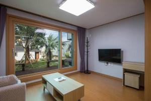 a living room with a couch and a large window at THE SOME PENSION in Seogwipo