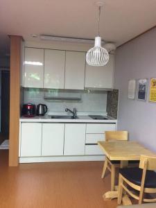 a kitchen with white cabinets and a wooden table at THE SOME PENSION in Seogwipo
