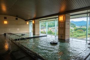 a large room with a pool of water with windows at KAMENOI HOTEL Ome in Ome