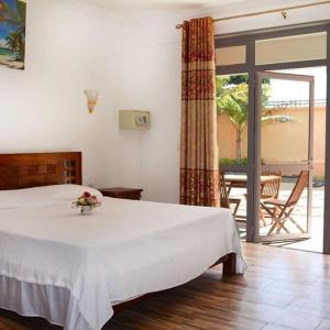 a bedroom with a white bed and a balcony at Easy Stay Residence in Trou aux Biches