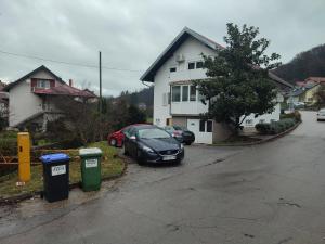 un coche aparcado en una entrada junto a dos cubos de basura en Apartman President en Krapinske Toplice