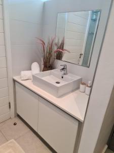 a white bathroom with a sink and a mirror at Umhlangha Oceans Dunes in Umhlanga