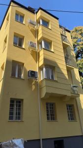 een geel gebouw met ramen en een straatlicht bij Graf Ignatiev Central Apartment in Sofia
