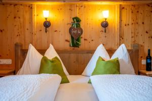 Schlafzimmer mit einem Bett mit weißer Bettwäsche und grünen Kissen in der Unterkunft Apartment Grammlergut in Maria Alm am Steinernen Meer