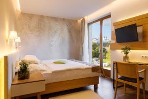 um quarto de hotel com uma cama, uma secretária e uma janela em Hotel Historia Malomkert em Veszprém