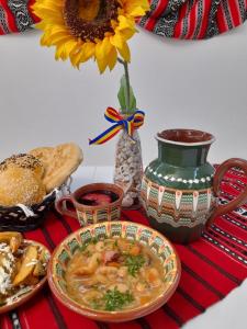 una mesa con un tazón de sopa y un jarrón con una flor en Hotel Dunavis, en Orşova