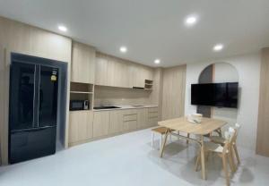 a kitchen with a wooden table and a black refrigerator at Mangkon Hostel in Bangkok