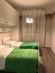 een slaapkamer met 2 bedden met groene lakens en een kroonluchter bij WHITE HOUSE in Verona