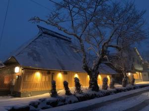 a building with lights in the snow at night at Hakuba Hatago Maruhachi in Hakuba
