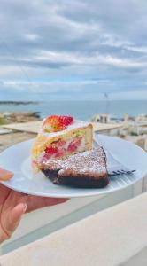 uma pessoa segurando um prato com um pedaço de bolo em FONTEblu B&B em Polignano a Mare