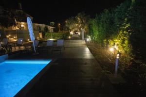 a backyard at night with a swimming pool and lights at 8 Boutique Suites in Nea Potidaea