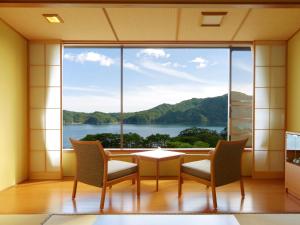 a room with a table and chairs and a large window at Jodogahama Park Hotel in Miyako