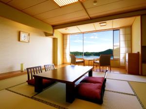 a room with a table and chairs and a large window at Jodogahama Park Hotel in Miyako