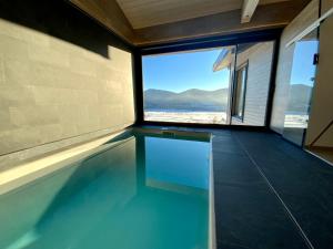 Artik chalet avec vue à 180 degrés et piscine في ليز أنغلز: حمام سباحة مع نافذة في المنزل