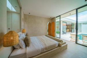 ein Schlafzimmer mit einem großen Bett und einem Balkon in der Unterkunft Villa Tilos - Stylish & Chic 2BR Mediterranean Villa in Canggu! in Canggu