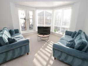 a living room with two blue couches and a tv at Beach House in Rhos-on-Sea