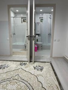 a bathroom with a shower and a toilet and a door at Guesthouse GreatHome in Karakol