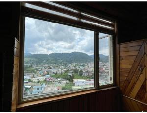 a window in a room with a view of a city at Hotel Mall Palace, Pithoragarh in Pithorāgarh
