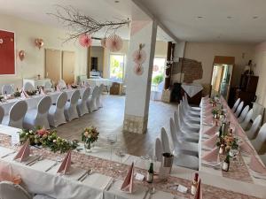 un salón de banquetes con mesas blancas y sillas blancas en Pension Elisabeth am Elberadweg en Prödel