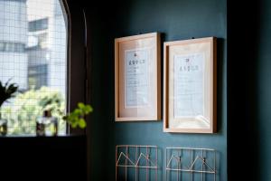 two framed pictures on a blue wall with a window at Queen Love Homestay in Hualien City