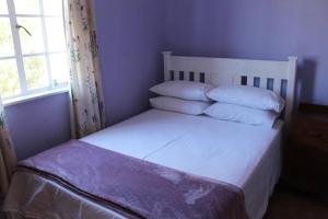Un dormitorio con una cama blanca con almohadas y una ventana en The Ark Sanctuary, en Napier