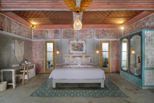 a bedroom with a bed and a desk and a mirror at Casa Batu Belig in Seminyak