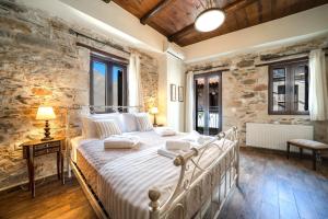 a bedroom with a white bed in a stone wall at Arhontariki Luxury Apartment in Panormos Rethymno