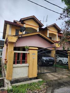 a yellow and pink house with a black fence at Homestay DeUmmah House in Cukai