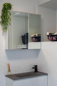 un armario blanco con espejo y lavabo en Condor Apartments by Gold Coast Premium, en Gold Coast