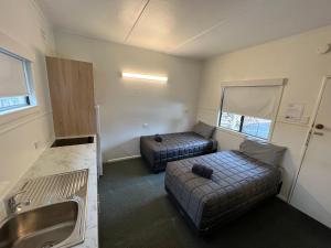 Habitación pequeña con 2 camas y lavamanos en Hi-Way Motel Grafton - Contactless, en Grafton