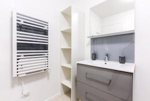 ein weißes Badezimmer mit einem Waschbecken und einem Spiegel in der Unterkunft Studio New York in Tourcoing