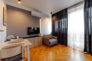 a living room with a television and a table and a chair at Kwiatowa Warsaw Apartment in Warsaw