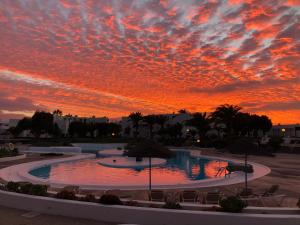 ein Sonnenuntergang über einem Pool auf einem Parkplatz in der Unterkunft Casa Yuma in Costa Teguise