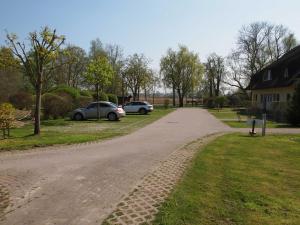 a dirt road with two cars parked in a yard at Sonniges Reetdachhaus in Puddemin