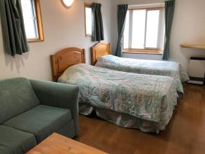 a hotel room with two beds and a couch at SkiHolic by TSH in Shinano