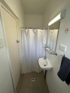 y baño blanco con lavabo y ducha. en Hi-Way Motel Grafton - Contactless, en Grafton