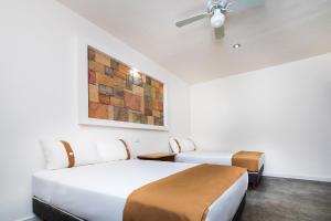 a room with two beds and a ceiling fan at Capital O Hotel Joyma Suites, San Luis in San Luis Potosí