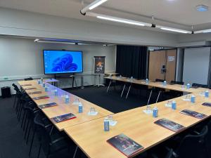 a large conference room with tables and a projection screen at ibis Saint-Lô in Saint Lo