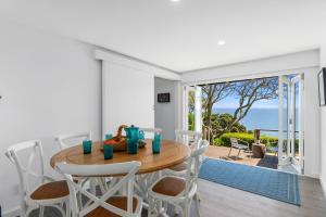 a dining room with a table and chairs and a view of the ocean at Bayview Bungalow - Nelson Holiday Home in Nelson